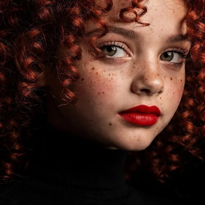 Portrait of a red-haired girl with freckles wearing bright red lipstick